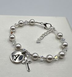 "This stunning bracelet is designed using 6mm white exquisite crystal pearls, 4mm AB Austrian Crystal, a pewter initial charm and a sterling silver cross with a cubic zirconia in the center!  This piece is finished with a sterling silver plated lobster clasp and soldered jump ring. A 1\" extender chain with a 4mm crystal dangle adds to this special piece. A wonderful keepsake for a Communion or Confirmation. If you don't see the size you need please let me know!" Elegant Silver Pearl Bracelet For First Communion, Classic Silver Rosary Bracelet As Gift, Silver Crystal Bracelet With Pearl Charm, Silver Pearl Charm Crystal Bracelet, Elegant Silver Name Bracelet With Round Beads, Silver Pearl Bracelets With 8mm Beads, Elegant Pearl Jewelry For Confirmation, Elegant Rosary Bracelet For First Communion With Round Beads, Elegant Rosary Bracelet With Round Beads For First Communion