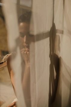 a man standing in front of a curtain with his hand on his face and looking at the camera