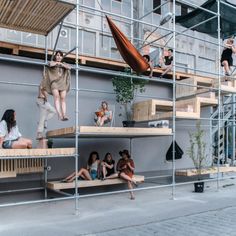 several people sitting on wooden benches in front of a building with scaffolding around them