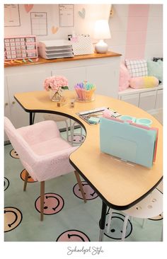 a desk with two chairs and a pink chair in front of it on top of a rug