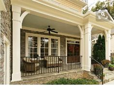 the front porch is decorated with stone and wrought iron railings