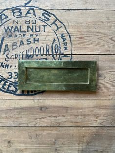 a close up of a metal door handle on a wooden wall with an old stamp