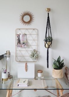 a glass table with some plants and pictures on the wall above it, along with other items