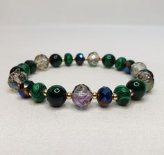 "The bracelet is made of crystals, glass, and gemstones and is beautifully handcrafted. Featuring vibrant crystal beads, malachite stone, green tiger eye, and 14 kt gold plated accent beads. With its versatile bead assortment, this bracelet goes with any outfit. You will be able to show off your unique style and make your wrist the center of attention. Most of my bracelets fit wrists between 6\" and 6.5\" in size. Before placing an order, please confirm your size. Thank you" Handmade Malachite Beaded Bracelets For Spiritual Use, Handmade Malachite Spiritual Beaded Bracelets, Spiritual Faceted Beads Crystal Bracelet For Jewelry Making, Crystal Gemstone Beaded Bracelets, Handmade Beaded Bracelets With Round Mineral Crystal Beads, Green Crystal Round Beads Bracelets, Green Crystal Beaded Bracelets With Round Beads, Faceted Beads Czech Glass Bracelets For Healing, Crystal Bracelet With Gemstone Beads