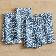 four blue and white napkins sitting on top of a wooden table