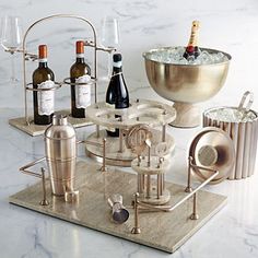 an assortment of wine bottles and glasses on a marble counter top with a metal mixer