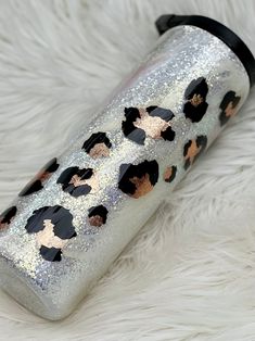 a silver and black glittered water bottle sitting on top of a white fur covered floor