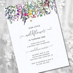 a white card with flowers on it and the words, our little wildflower is turning one