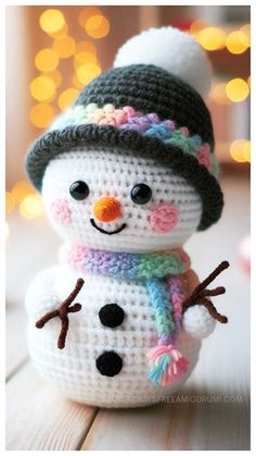 a crocheted snowman sitting on top of a wooden table