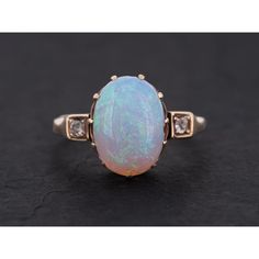 an opalite and diamond ring on a black surface with gold trimmings