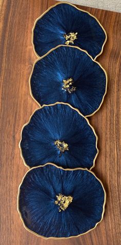 three blue plates sitting on top of a wooden table covered in gold trimmings