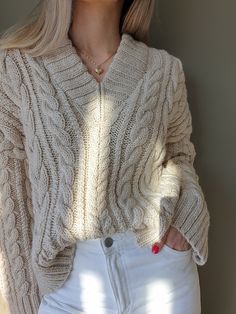 a woman with blonde hair wearing white jeans and a cable knit sweater is posing for the camera