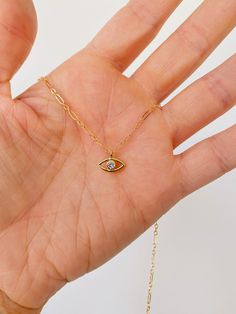 Petite gold CZ evil eye necklace pendant on gold filled chain. Gold fill charm with one tiny CZ in the center of the eye. Perfect dainty piece to wear alone or layer. Available 15” to 18” in length. Gold fill lobster clasp. Everyday Yellow Gold Evil Eye Charm Necklaces, Everyday Evil Eye Charm Necklaces, Dainty 14k Gold Charm Necklace With Evil Eye, Gold Dainty Evil Eye Charm Necklace, Gold Evil Eye Charm Necklace For Everyday, Everyday Gold Charm Necklaces With Evil Eye, Dainty Yellow Gold Evil Eye Charm Necklace, Everyday Gold Charm Necklace With Evil Eye, Evil Eye Necklace