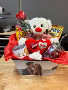 a teddy bear sitting in a basket filled with snacks and candys on a white background