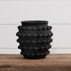 a black vase sitting on top of a wooden table