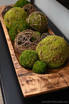 moss covered balls are sitting on a wooden platter