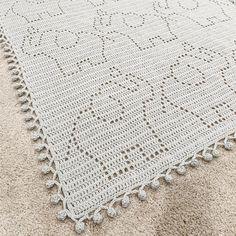 a white crocheted rug on the floor with a beige carpet and tan walls