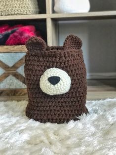 a crocheted brown bear hat sitting on top of a white rug