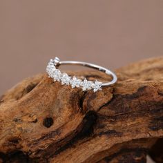 a white gold and diamond ring on top of a piece of driftwood with the word love written in it