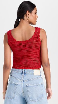 a woman wearing a red crochet top and denim shorts with her back turned to the camera