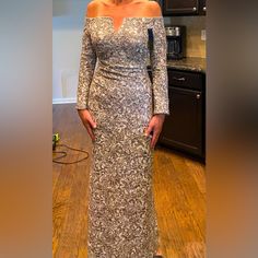 a woman standing in a kitchen wearing a dress with an off the shoulder neckline