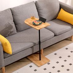 a gray couch with yellow pillows and a wooden tray on it's end table