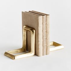 three brass bookends on white background with one leaning against the other, both holding books