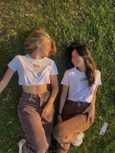 two young women laying on the grass next to each other