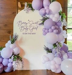 balloons and greenery decorate the backdrop for a baby shower