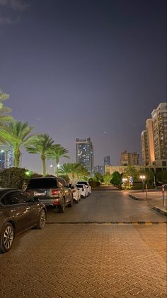 several cars parked on the side of a road at night with palm trees in the background