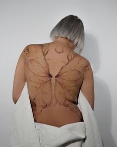 the back of a woman's body with butterfly tattoos on her shoulder and chest