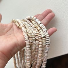 a hand is holding several bracelets made from seashells and other sea shells