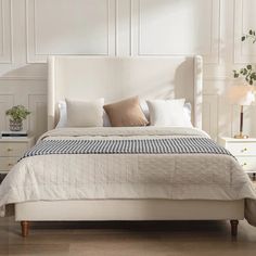 a white bed sitting in a bedroom next to a dresser and lamp on top of a hard wood floor