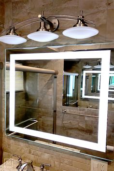 a bathroom vanity with three lights and a large mirror