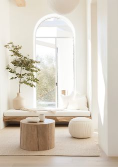 a living room with white furniture and a large window in the corner, along with a round coffee table