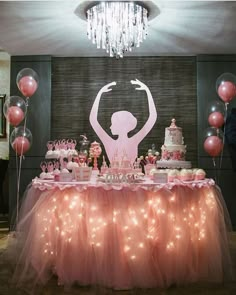 a table topped with pink cake and balloons