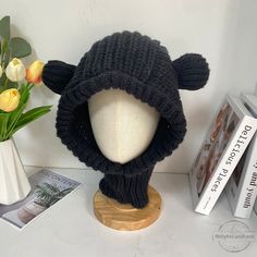 a knitted hat with ears is sitting on a table next to books and flowers