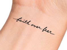 the word faith over fear written in cursive handwriting on a woman's wrist