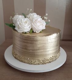 there is a gold cake with white flowers on it