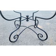 an iron table with curved legs on the ground