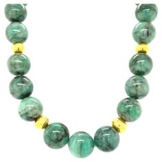 This impressive strand of emerald beads showcases a stunning combination of elegant green and bright yellow gold that is flattering to all complexions! The 15mm round emerald beads have beautiful black veining that gives the necklace a gorgeous dramatic effect. Rich 22kt yellow gold beads with their hammered finish add a luxurious feel to this necklace that is suitable both for daytime and evening wear. A lovely 14k yellow gold hammered ball clasp completes the necklace perfectly. 18 inches fini Luxury Emerald Necklace With Polished Beads, Luxury Beaded Necklace With Oval And Spacer Beads, Affordable Pearl Necklace With Round Gemstone Beads, Luxury Green Large Beaded Jewelry, Luxury Artisan Beaded Necklace With Round Beads, Luxury Traditional Round Beads, Luxury Green Round Beads, Luxury Gold Jewelry With Round Beads, Luxury Beaded Round Emerald Necklace