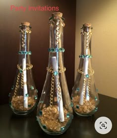 three glass vases filled with sand and candles on a table next to a wall