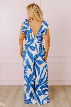 - Perfect for a sunny stroll, this fabulous jumpsuit will boost your confidence! - Material with an abstract print - A v-cut neckline and back - A sleeveless cut featuring tie closure straps - A wide banded waistline with an elastic back - Back zip closure - A built-in lining that ends above the knee - A flowy and flattering silhouette that ends in wide hemlines Summer V-neck Jumpsuits And Rompers With Tie Back, Sleeveless Tie-back Jumpsuits And Rompers For Vacation, Sleeveless Tie Back Jumpsuit For Vacation, V-neck Tie-back Jumpsuits And Rompers For Vacation, V-neck Tie Back Jumpsuit For Vacation, V-neck Tie-back Jumpsuit For Vacation, Blue Sleeveless Tie Back Jumpsuit, Capri Jumpsuit, Boost Your Confidence