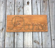 a wooden sign that says dance on it with rope around the word'dance '