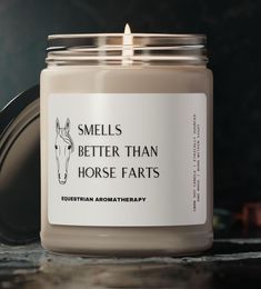 a candle that is sitting on a table with the words smells better than horse parts