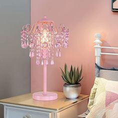 a pink lamp sitting on top of a table next to a bed