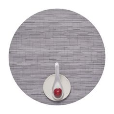 a white plate with a red ball in it on a gray place mat that looks like an oval