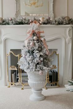 a decorated christmas tree in a white urn with pink bows and ornaments on top