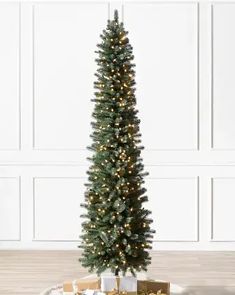 a christmas tree with presents under it on a tray in front of a white wall