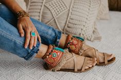 a woman sitting on top of a bed wearing sandals and holding her hands in her pockets